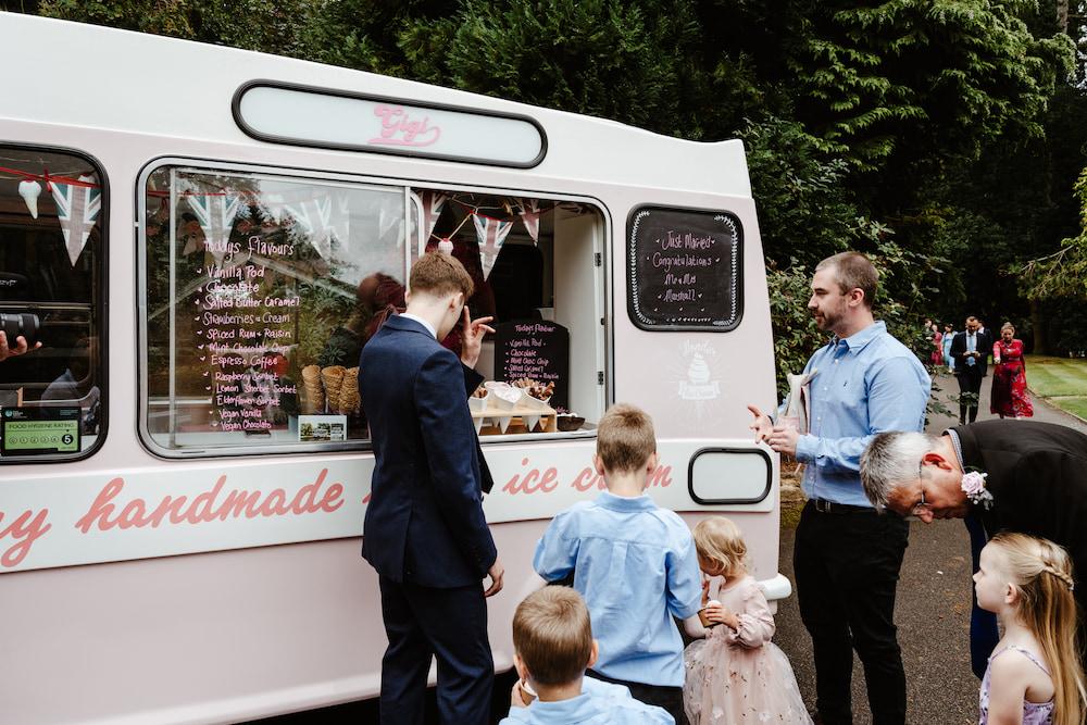 Pink ice cream van with children and their fathers buying ice cream.